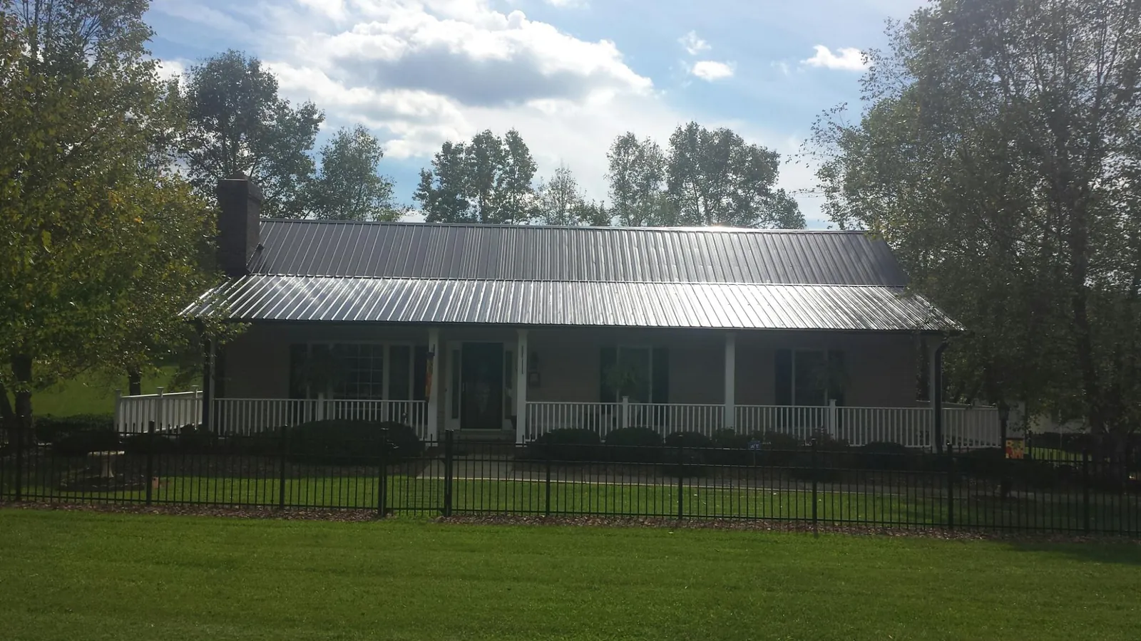 Gray metal roof on a brick ranch with a full width front porch — Gutter Guard Installation work by our crew in Chadbourn