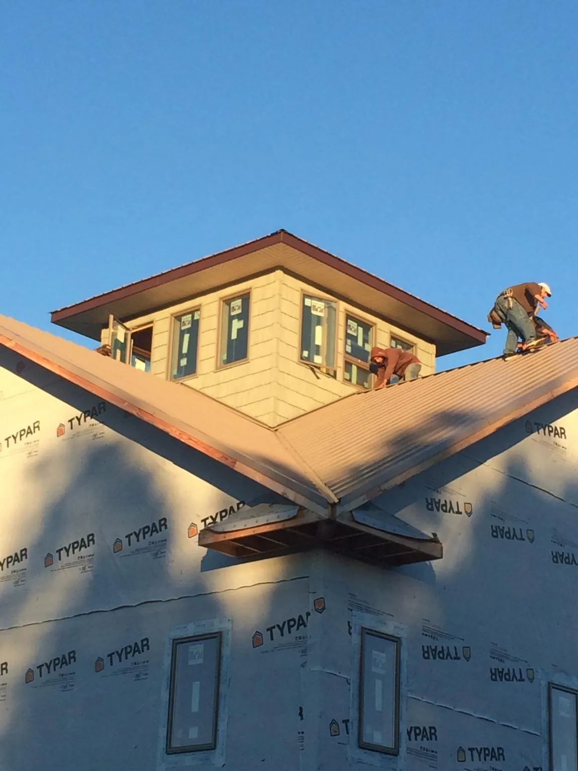 Roofers working around a rooftop cupola on a new metal roof at sunset — Roof Waterproofing in Chadbourn by Roofing Brothers